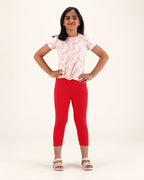 Front view of girls’ red capri leggings, styled with a floral top and sandals.