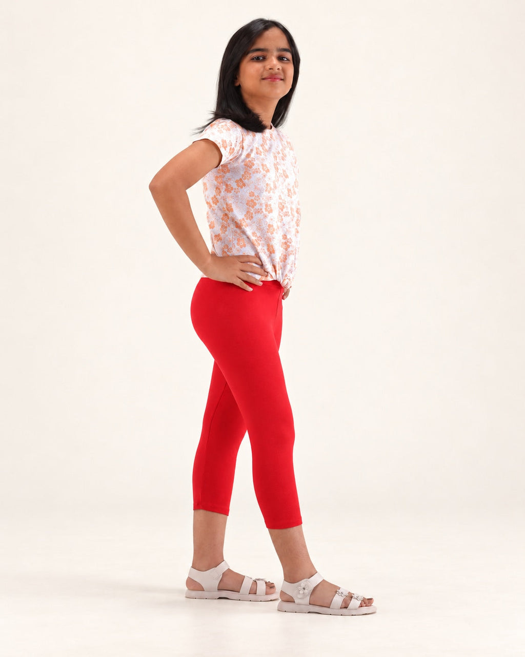 Three-quarter view of girls’ red capri leggings, showing the fit and capri-length hems.