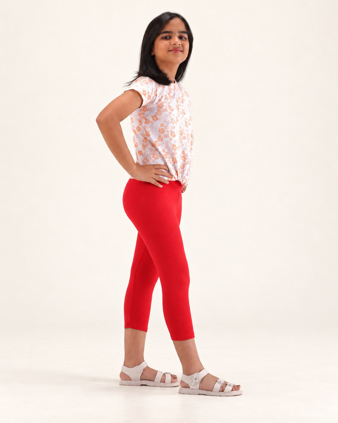Three-quarter view of girls’ red capri leggings, showing the fit and capri-length hems.